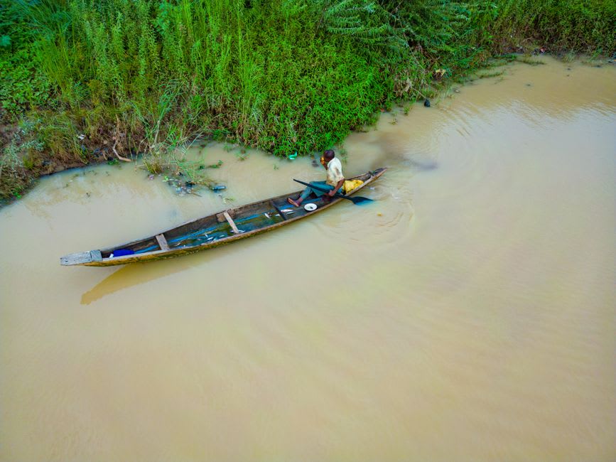 Canoas de madera talladas en tronco alineadas en la orilla fangosa del río Akobo al atardecer