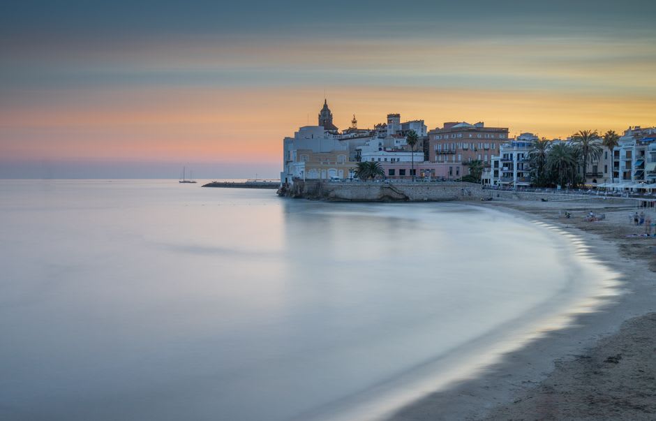 Iglesia barroca de Sant Bartomeu i Santa Tecla sobre su promontorio rocoso encima de la playa de Sitges al atardecer