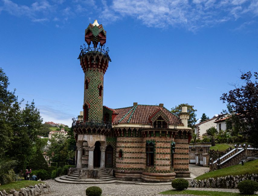 La torre de azulejos con girasoles de El Capricho de Gaudí elevándose sobre el verdor del jardín en Comillas