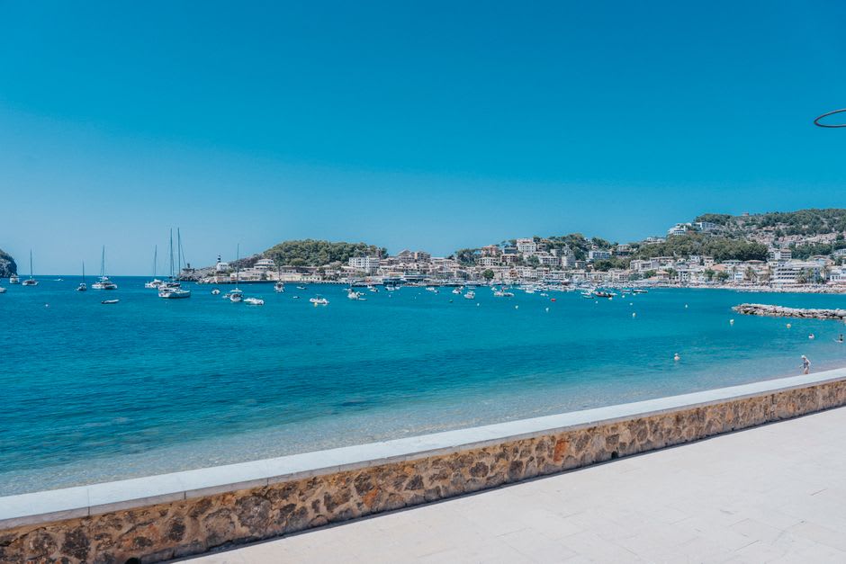 Port de Sóller's horseshoe-shaped bay with the Torre Picada watchtower and calm turquoise water at dusk