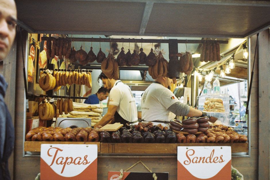 A Saturday market stall selling cured sausages and cheese under the arcades of Vic's Plaça Major