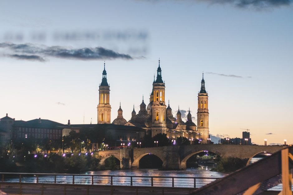 El puente de piedra medieval sobre el río Duero al atardecer con el casco antiguo de Zamora recortado al fondo