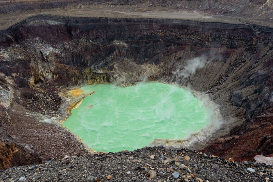 Deriba Crater's twin volcanic lakes seen from the rim of the Jebel Marra massif, still water reflecting the surrounding hills