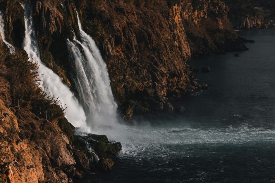 Water crashing down the sheer black cliff face of Cascade de Kpimé into the pool below