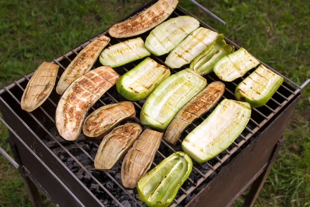 A sizzling Adana kebab grilling over charcoal, served with grilled tomatoes and peppers