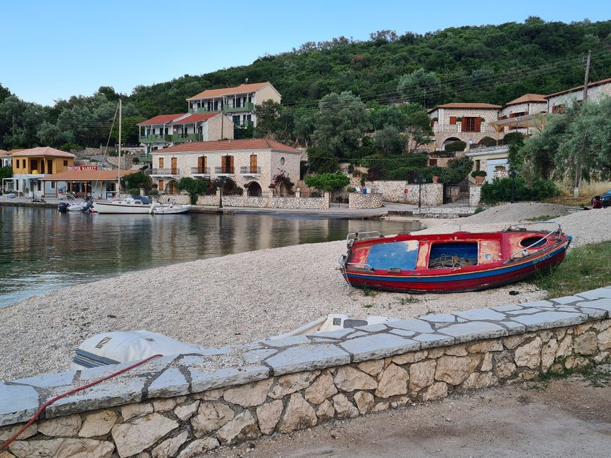 The small stone fishing harbor of Assos with boats moored below the cliffside ancient city