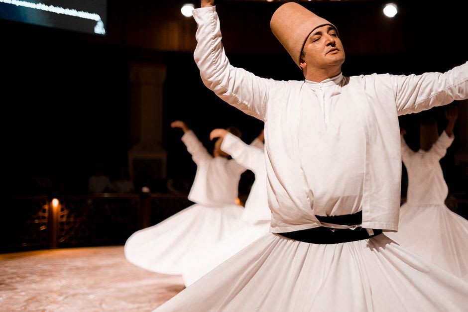 Derviches giróvagos representando la ceremonia sema, túnicas blancas girando en movimiento