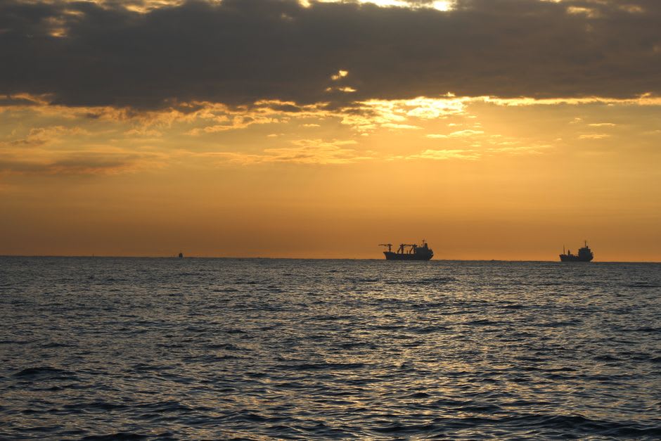 El malecón de Mersin al anochecer con barcos de carga anclados mar adentro
