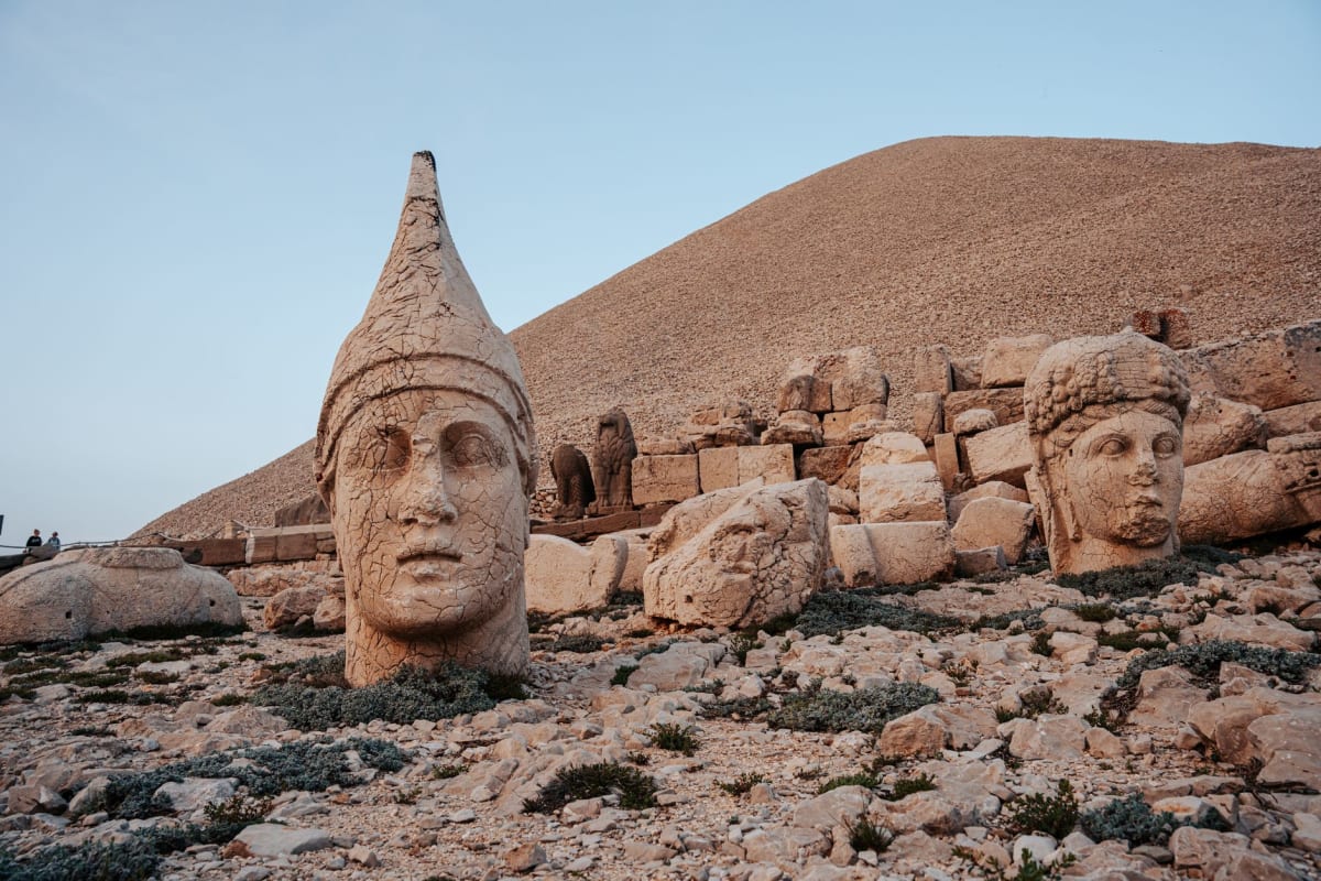 The stone faces in silhouette against a deep blue pre-dawn sky, the horizon beginning to lighten orange above the mountains to the east
