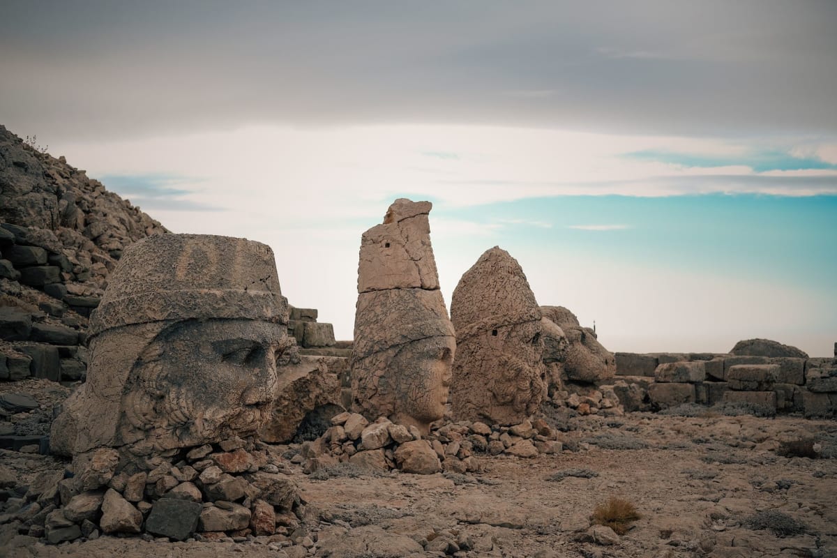 The heads on the West Terrace in softer morning light, with a carved stone relief of Antiochus and the gods visible in the background