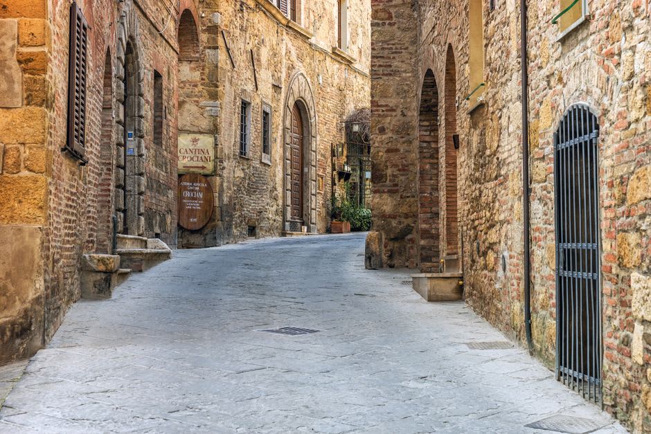 Una puerta de bodega de piedra en una calle de Montepulciano con barriles de vino visibles en el interior