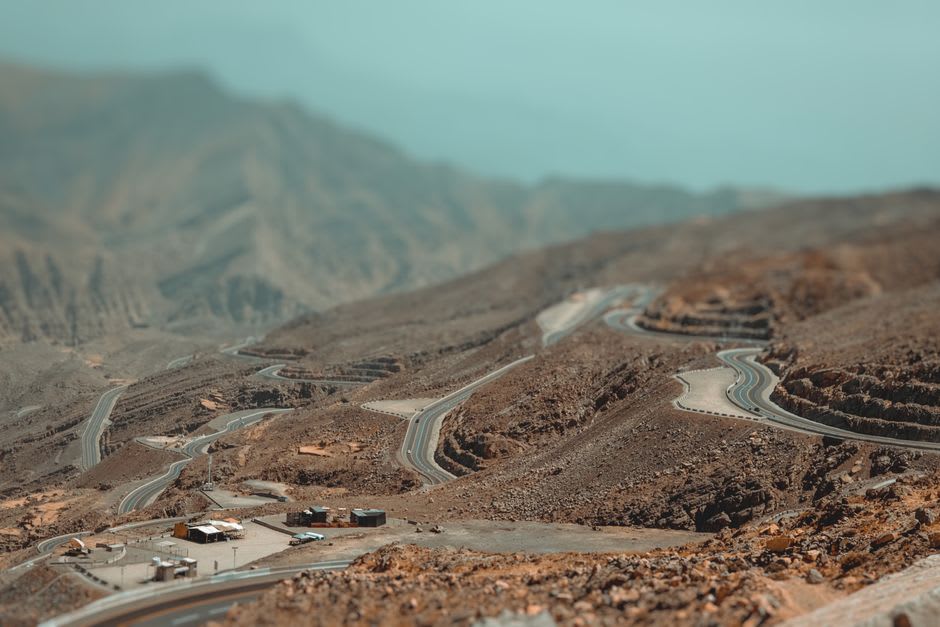 Sinuoso camino de montaña con curvas cerradas atravesando las laderas rocosas de Jebel Jais