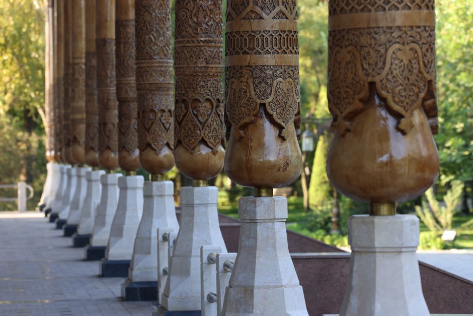 Carved wooden columns and painted ceiling inside the entrance hall of Khudayar Khan Palace