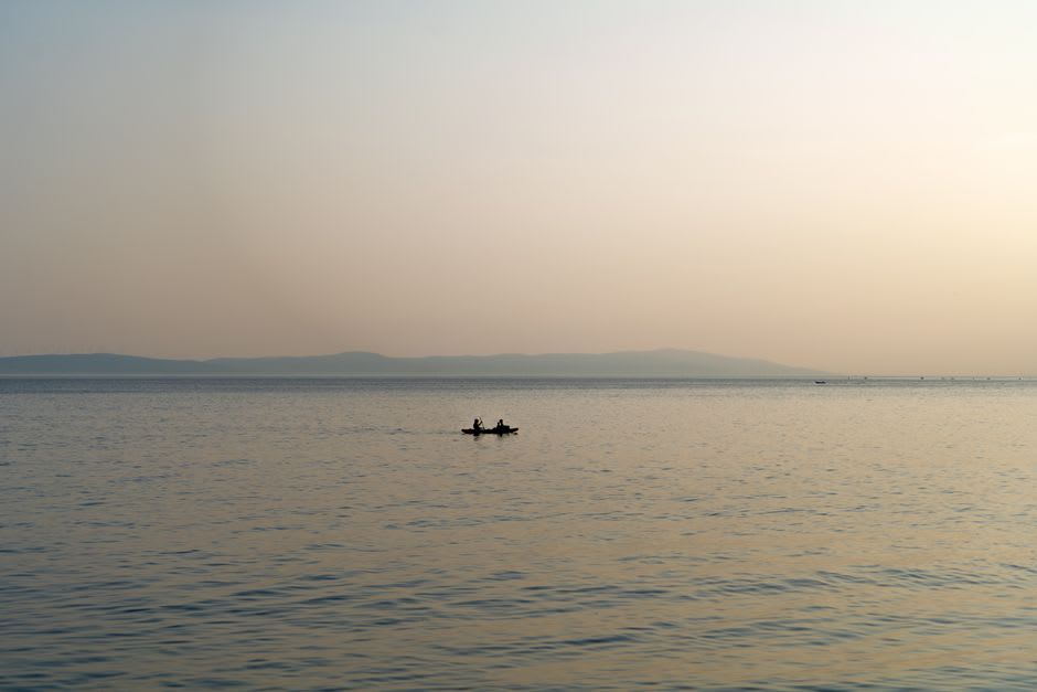 Wide view of Lake Kariba at sunset with a small fishing canoe silhouetted on calm water