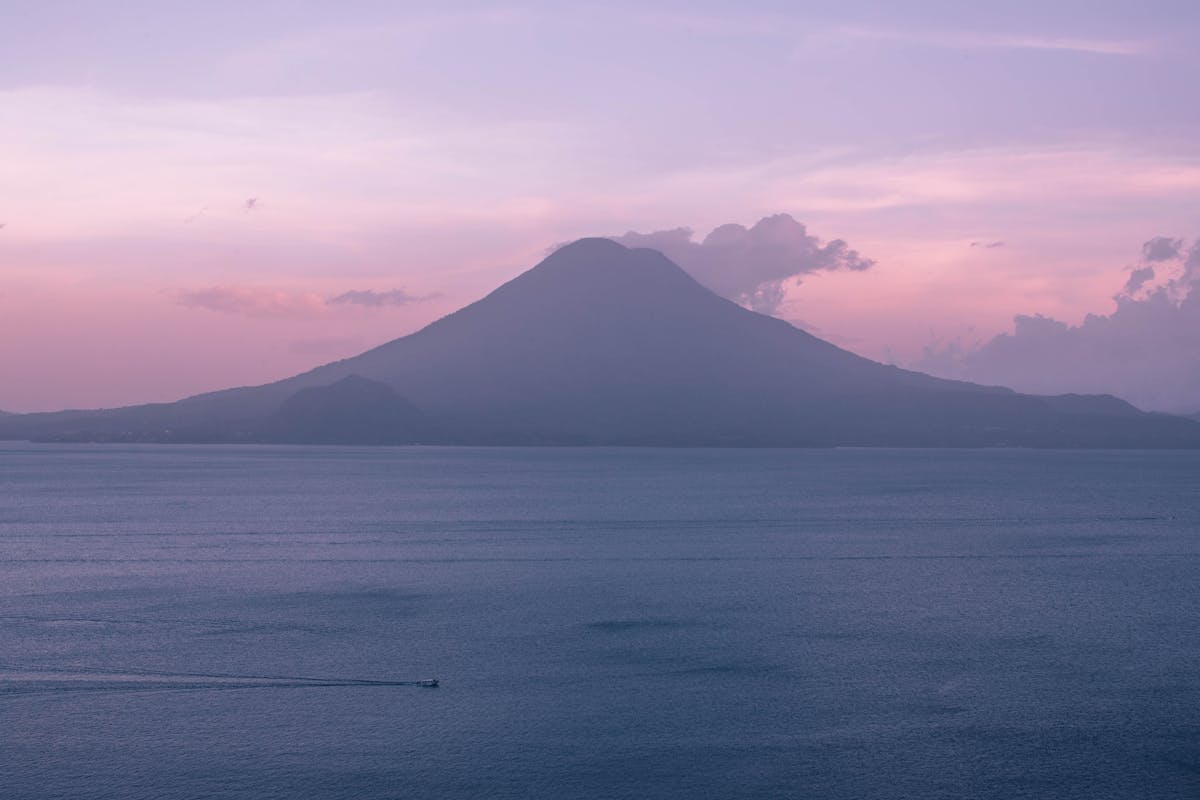 Lake Atitlán at dawn with volcanic peaks rising through the mist
