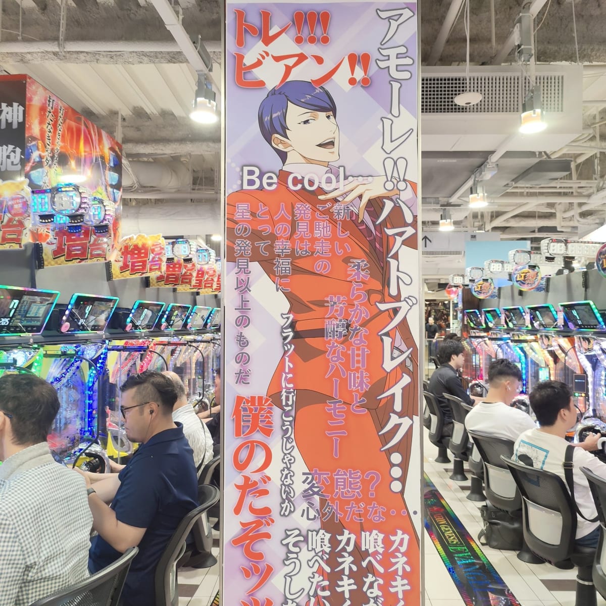 Rows of players at pachinko machines inside a Ueno parlor, an Evangelion-themed display and neon signage overhead