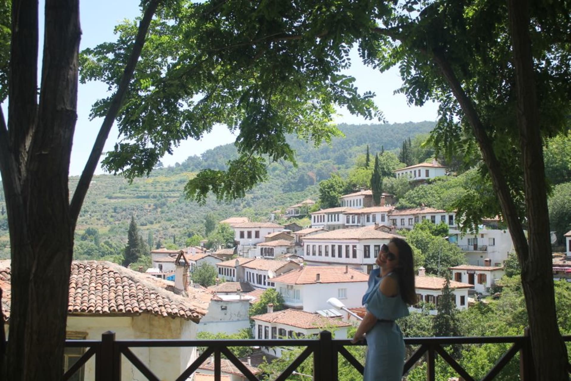 Stone houses with red tile roofs climbing the terraced hillside of Şirince village, surrounded by vineyards under soft afternoon light