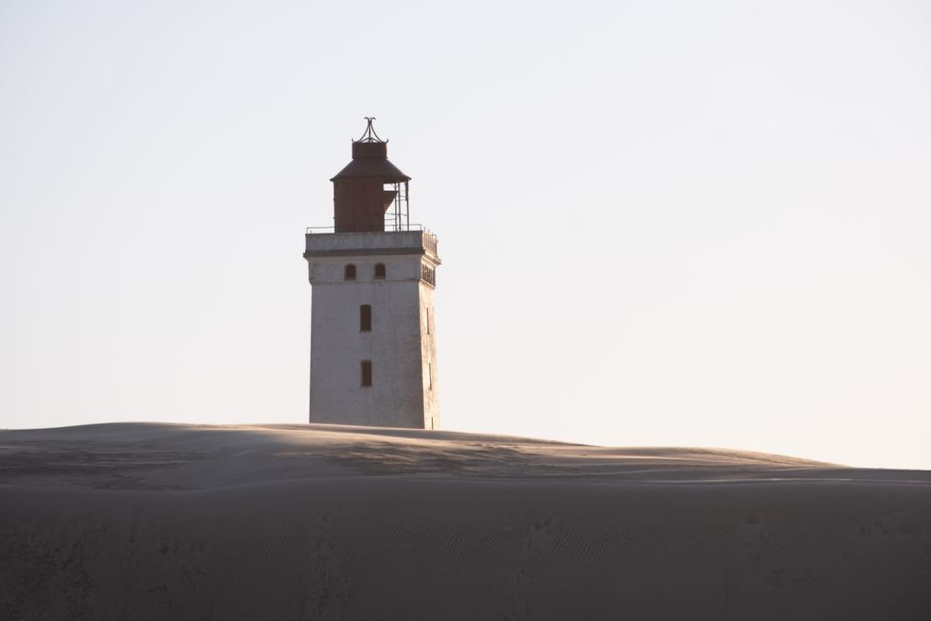 White lighthouse and red pilot station buildings on the treeless, wind-swept island of Signilskär surrounded by open sea