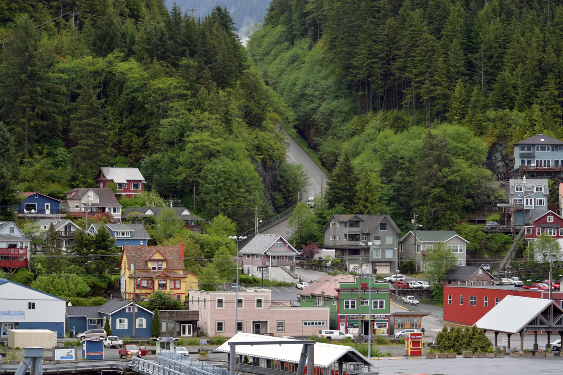 Ketchikan's colorful Creek Street boardwalk buildings built on stilts over Ketchikan Creek with a totem pole visible nearby
