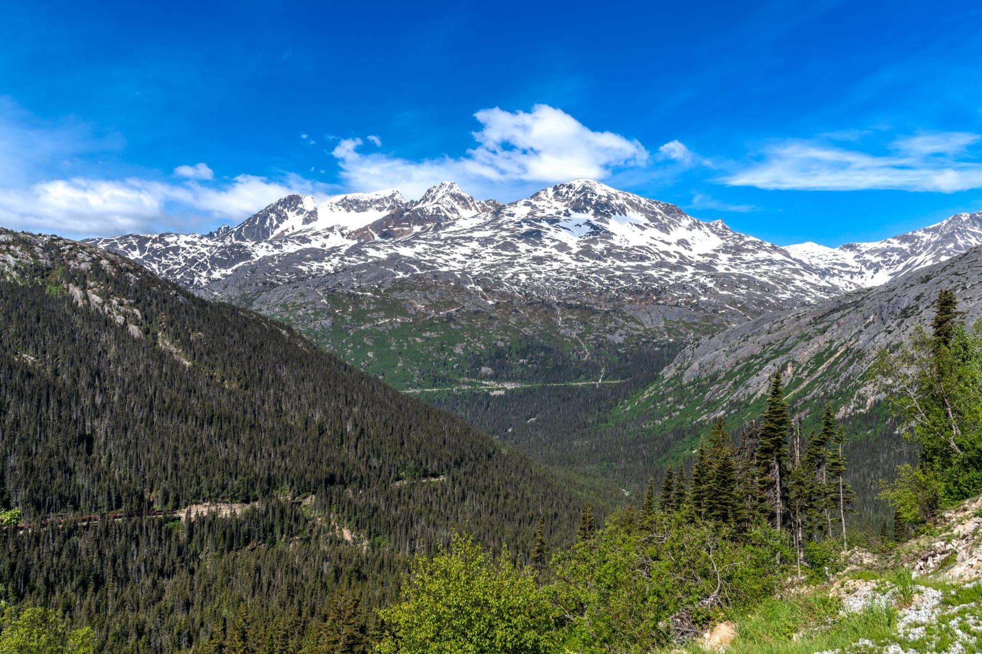 Skagway's historic Broadway lined with restored false-front wooden buildings beneath steep snow-streaked mountains