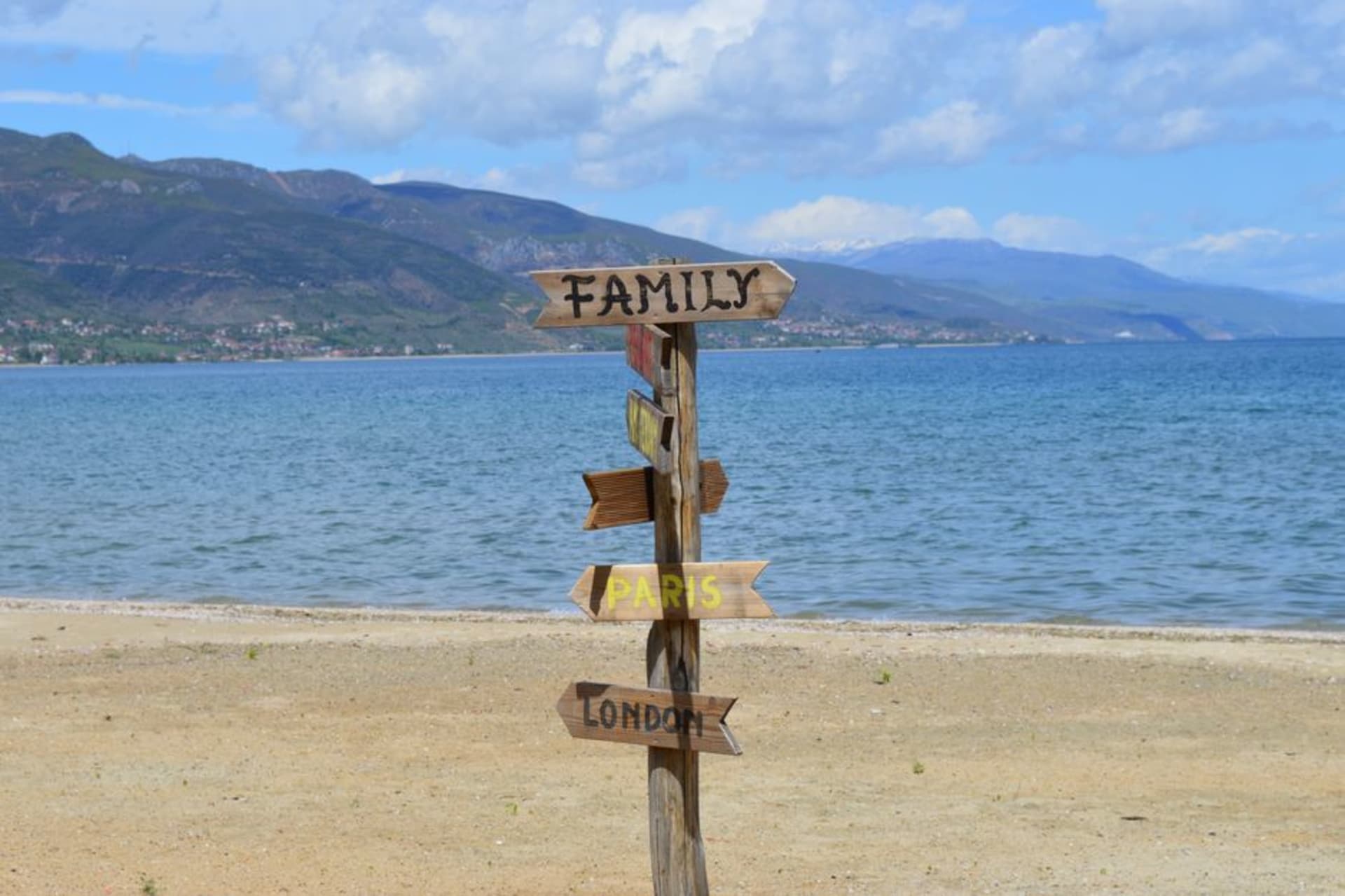 Las aguas azules y transparentes del lago Ohrid vistas desde el paseo de Pogradec, con montañas alzándose en la orilla norte macedonia al fondo.