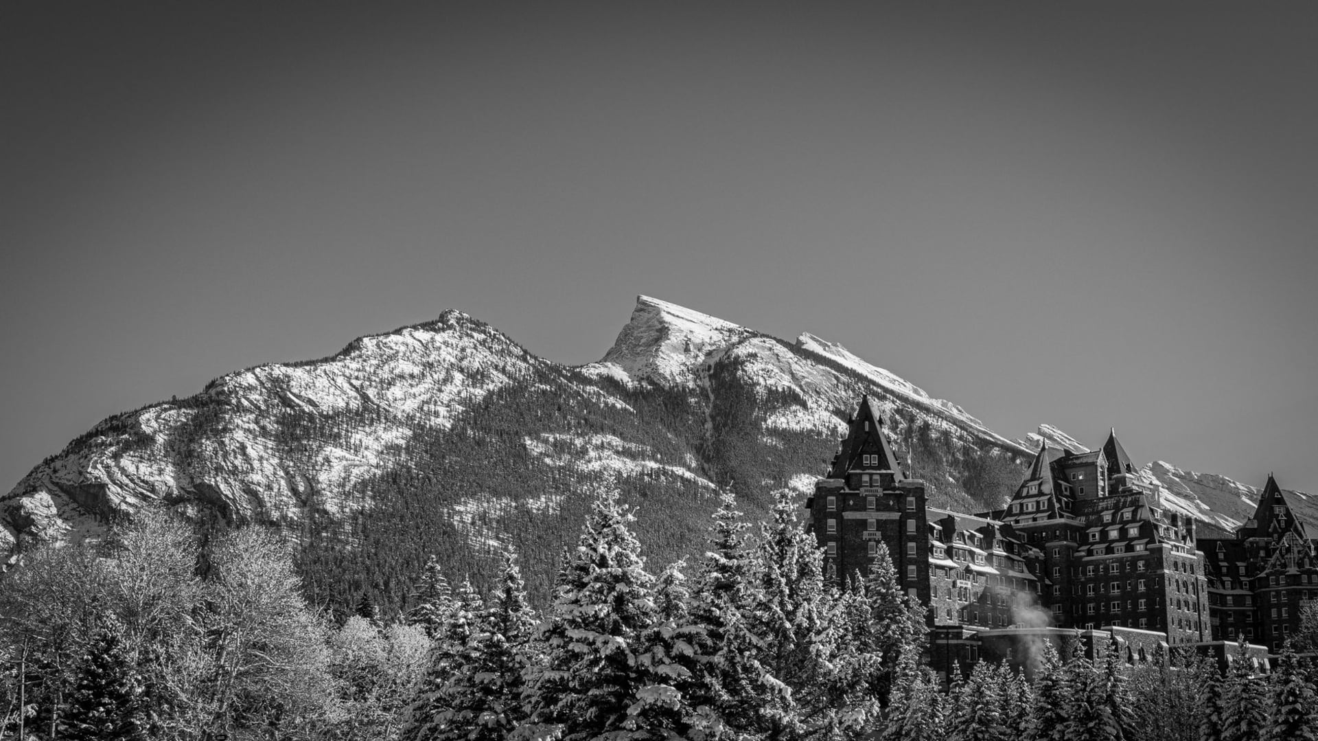 Banff Avenue at dusk with the snow-capped peaks of Mount Rundle glowing orange in the last light