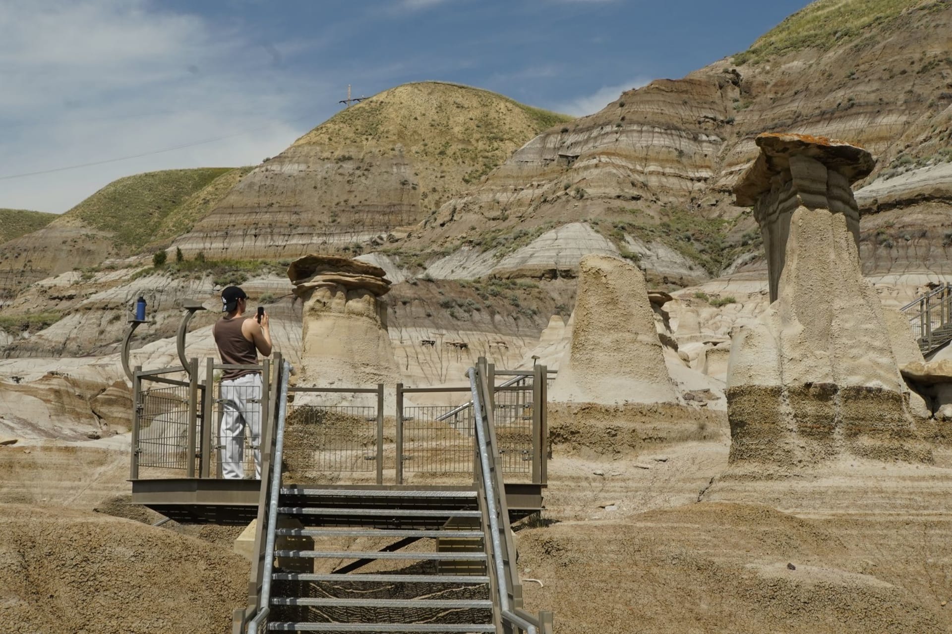 The Drumheller badlands at golden hour, hoodoo rock formations casting long shadows across the eroded valley floor, the Red Deer River winding far below