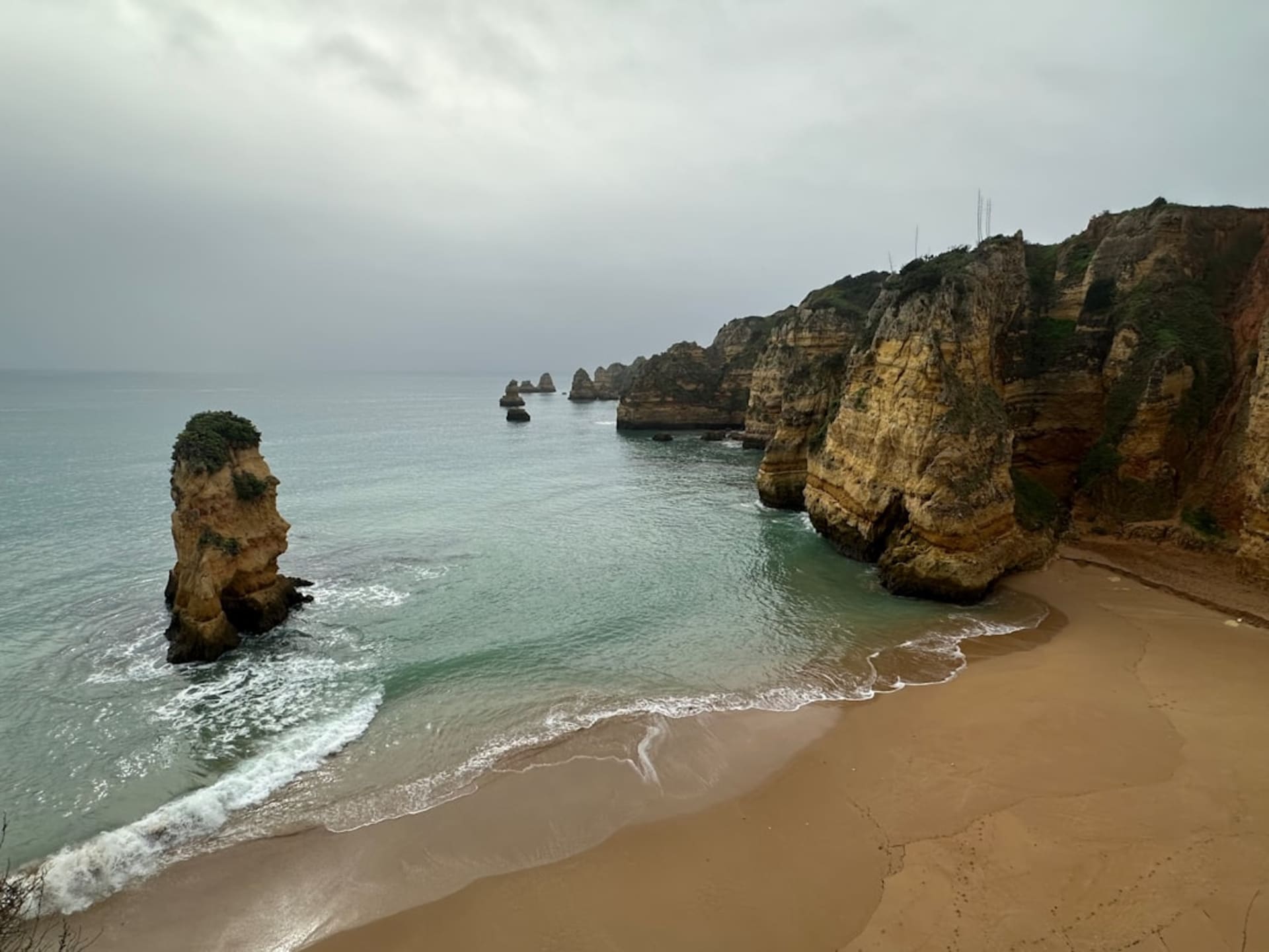 Sunlight streaming through the natural oculus of Benagil Cave onto the golden sand below