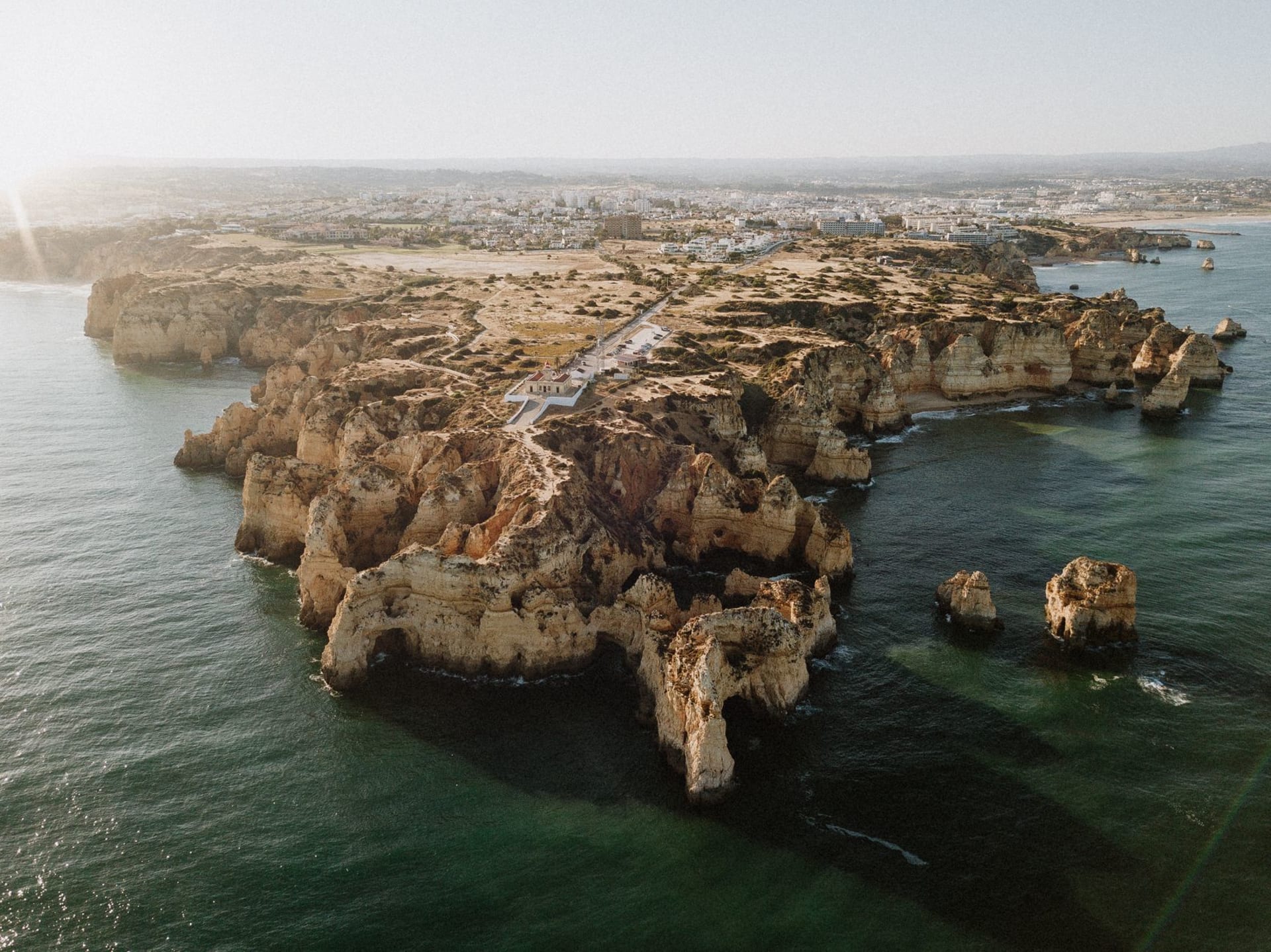 Twin golden sandstone sea arches at Ponta da Piedade reflected in turquoise water, viewed from sea level at morning light