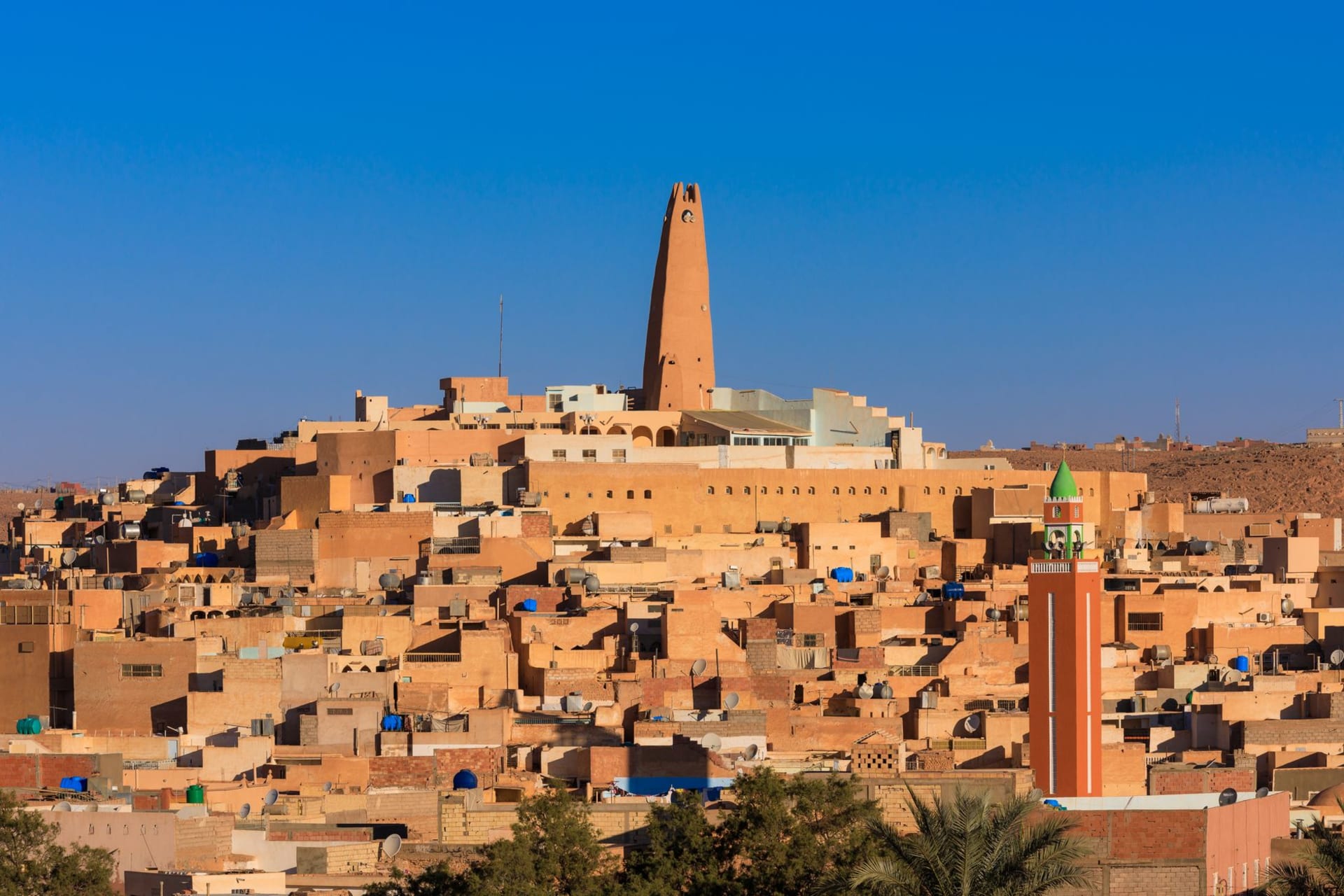 Pyramid of white and ochre Mozabite buildings with a distinctive pointed minaret rising above Ghardaïa in the M'zab Valley at dusk