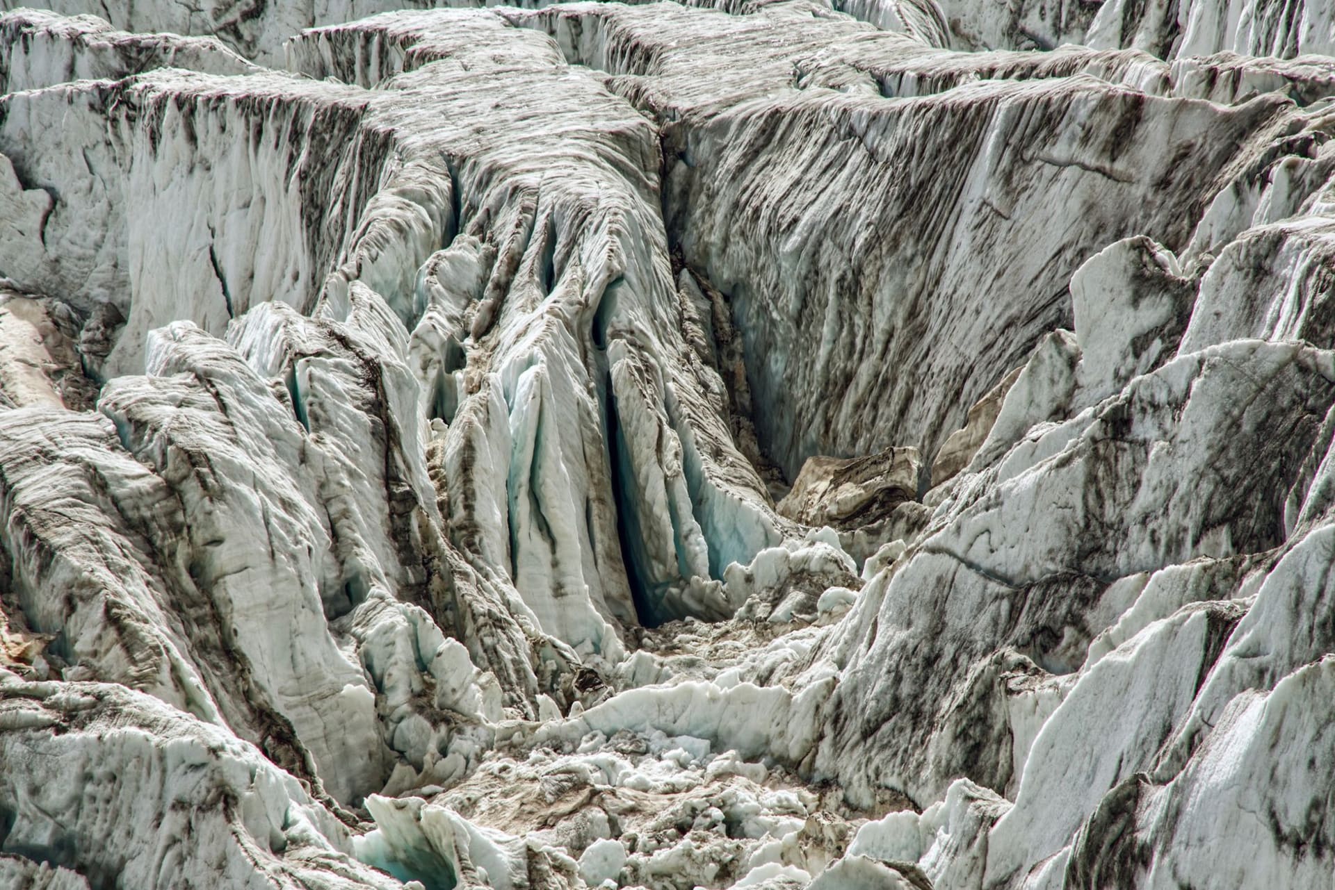 The Aktru glacier flowing between dark rocky ridges in the North Chuysky Range, crevassed and blue-white in the midday light