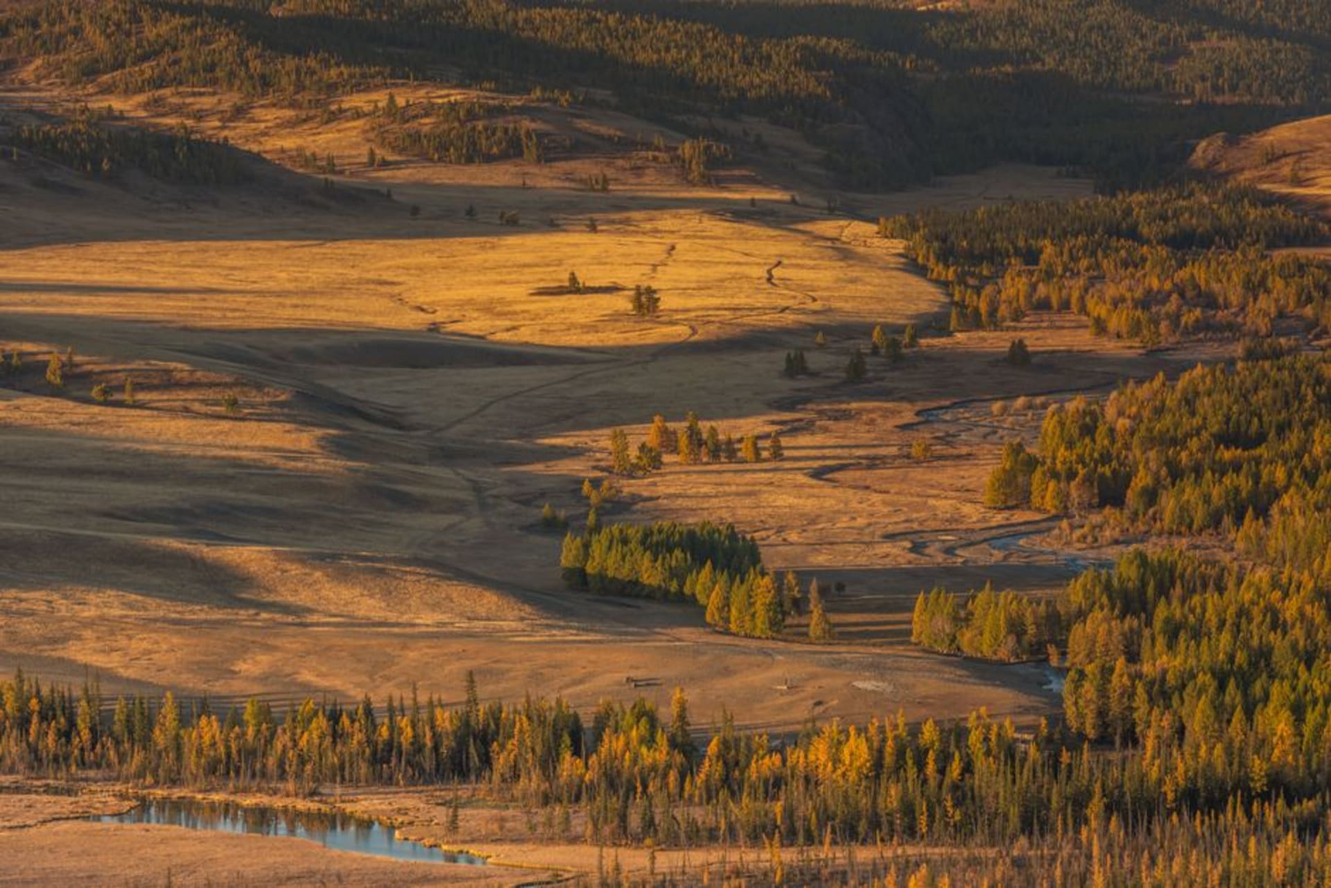 Striped red, yellow and green mineral slopes of Kyzyl-Chin Valley under a wide Altai sky