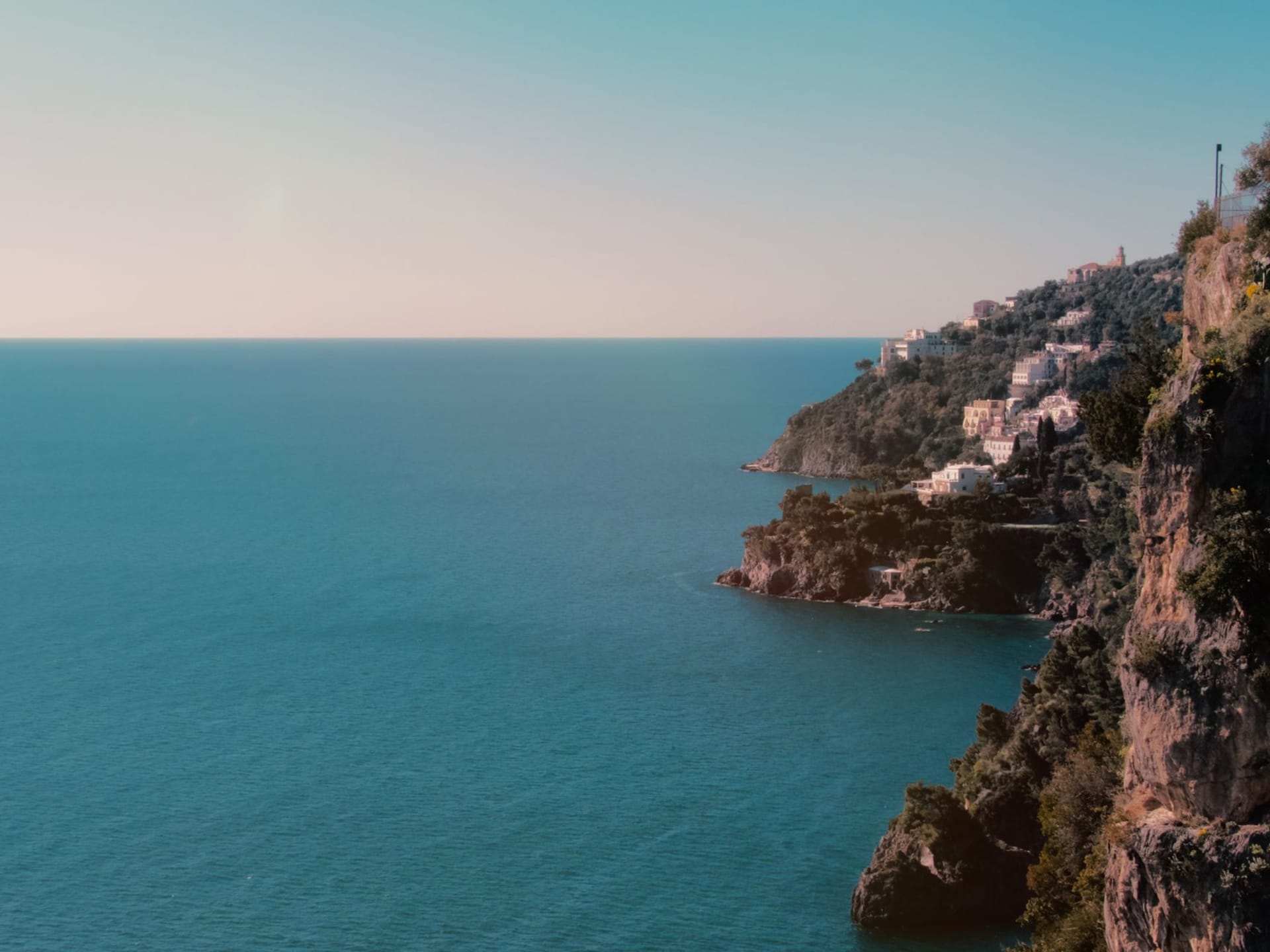 Colorful cliffside village on the Amalfi Coast with terracotta rooftops cascading toward a turquoise bay