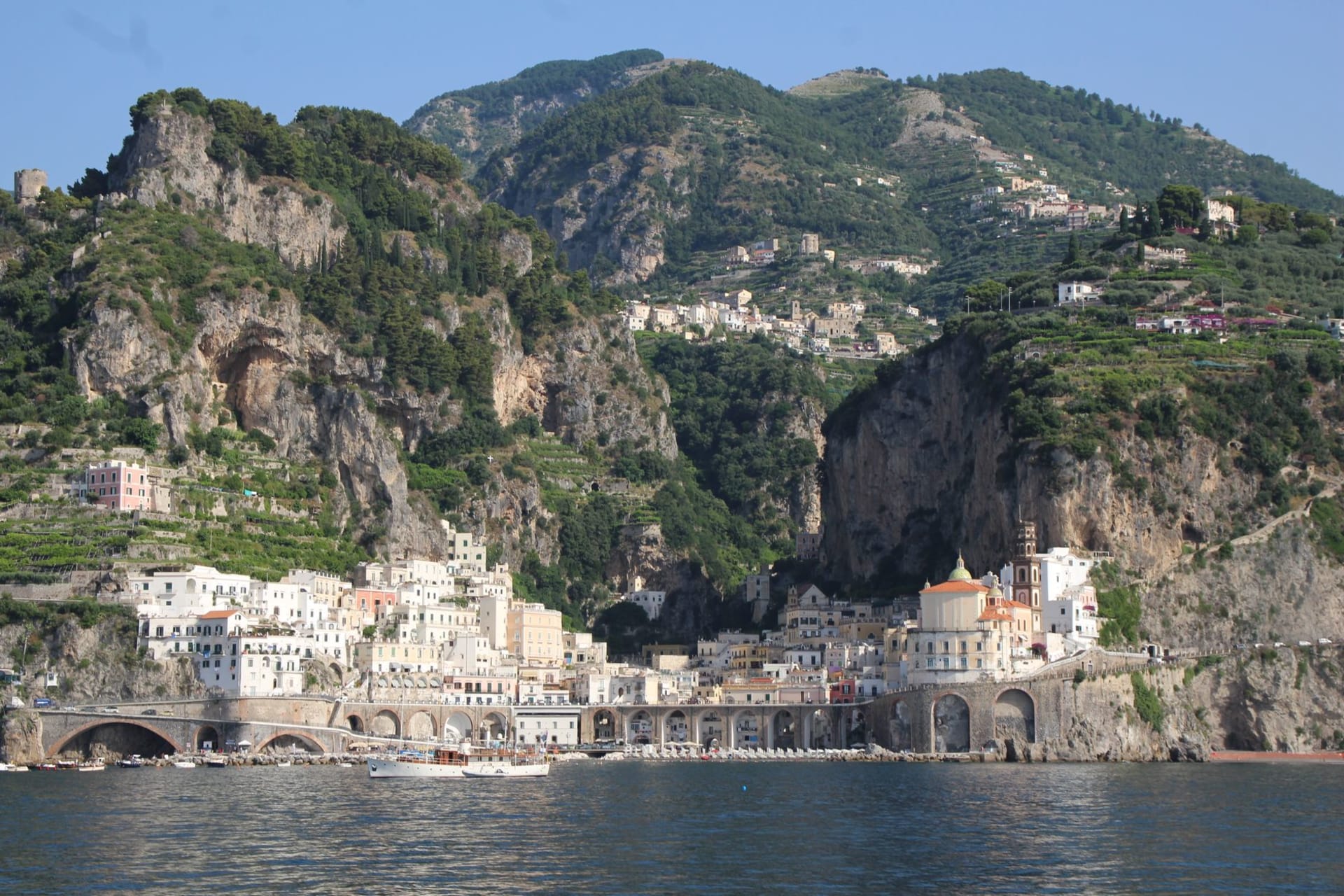 The Duomo di Sant'Andrea in Amalfi's main piazza with its Arab-Norman striped facade and grand staircase, surrounded by pastel buildings