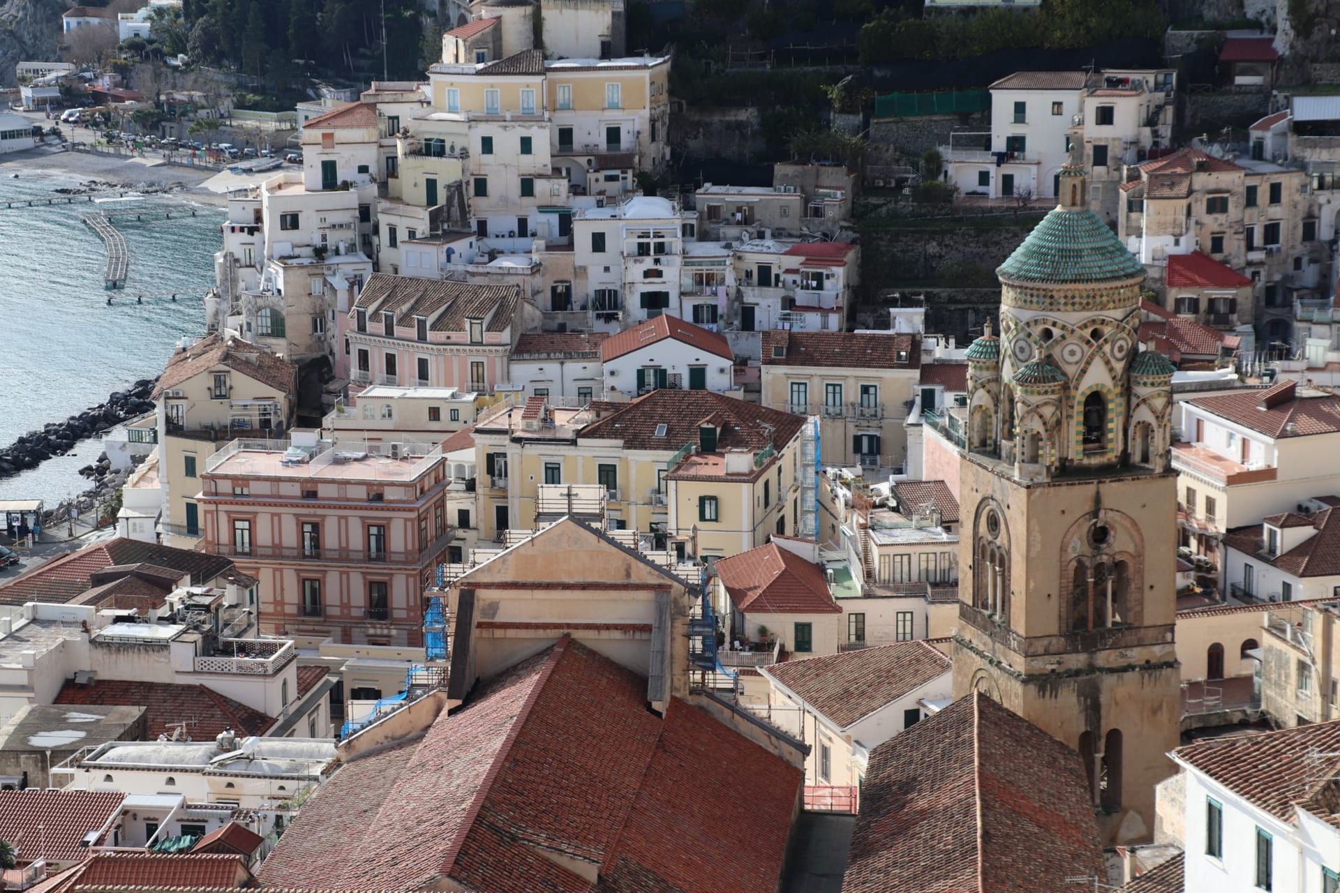 Cetara's compact harbor with painted fishing boats and the majolica-domed church tower rising behind colorful fishermen's houses