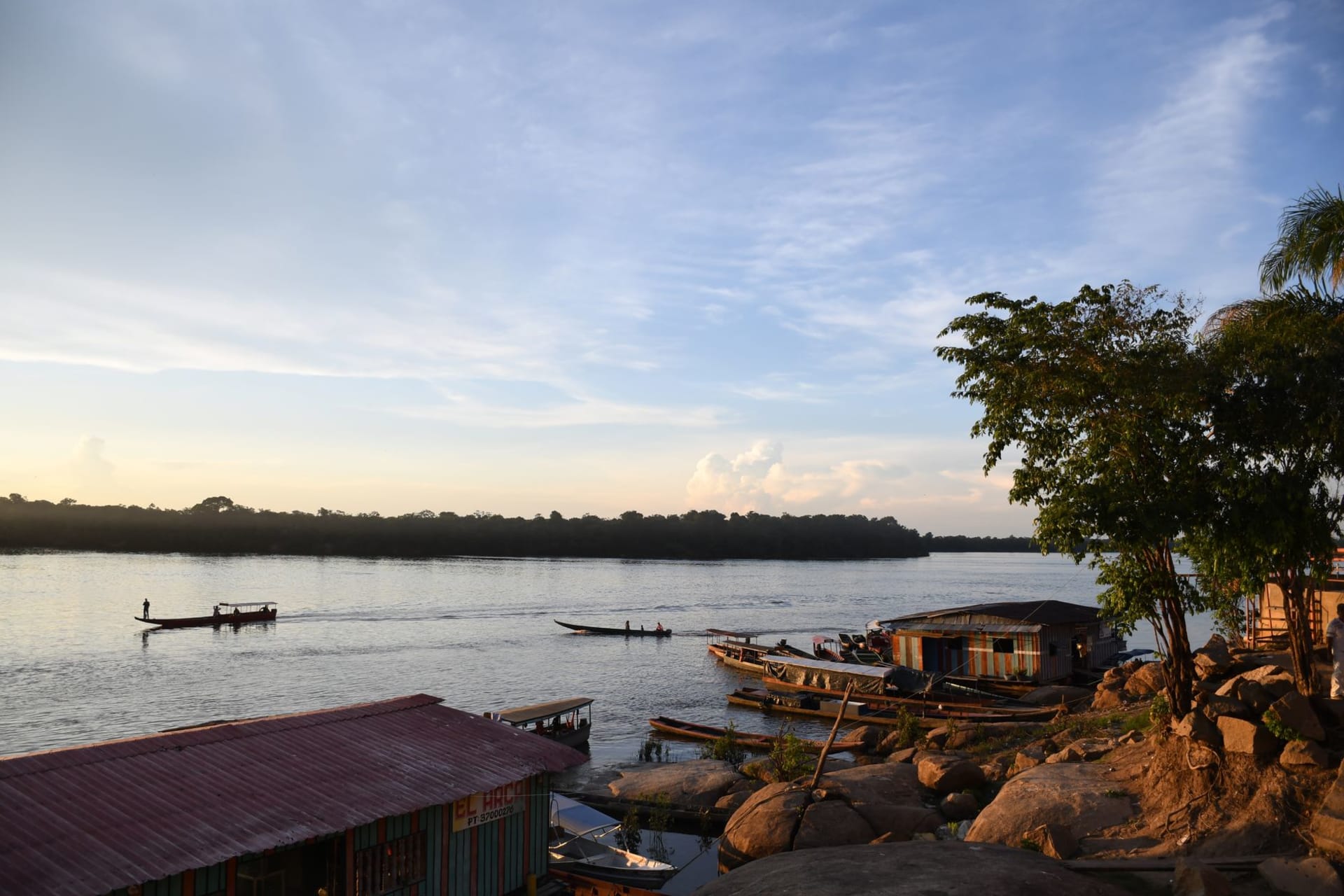 Wooden stilt houses along the muddy bank of the Putumayo River at Tarapacá with dense rainforest behind