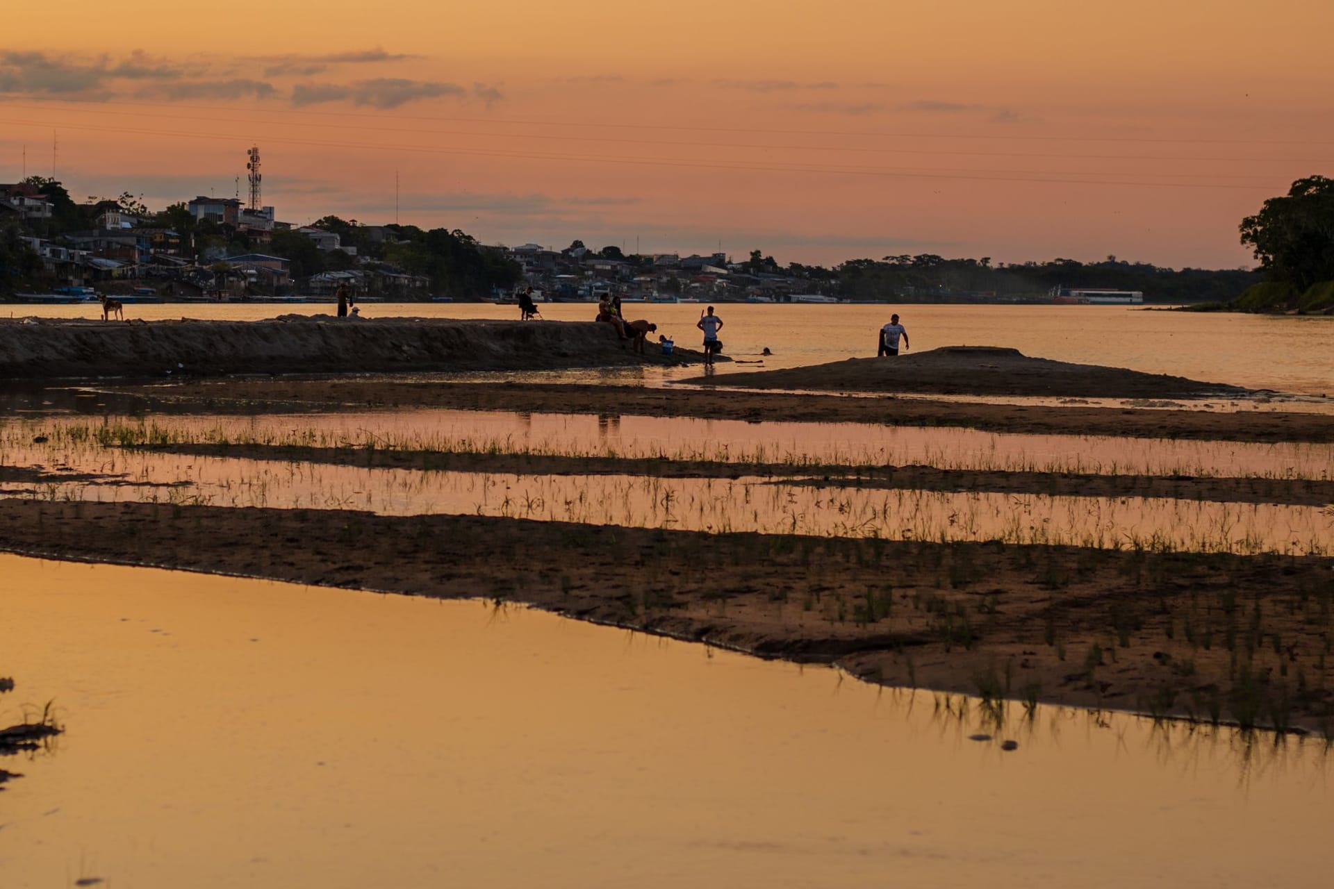 Yurimaguas harbor at dusk with cargo boats loading on the Huallaga River, mist rising from the water as the sun drops behind the jungle