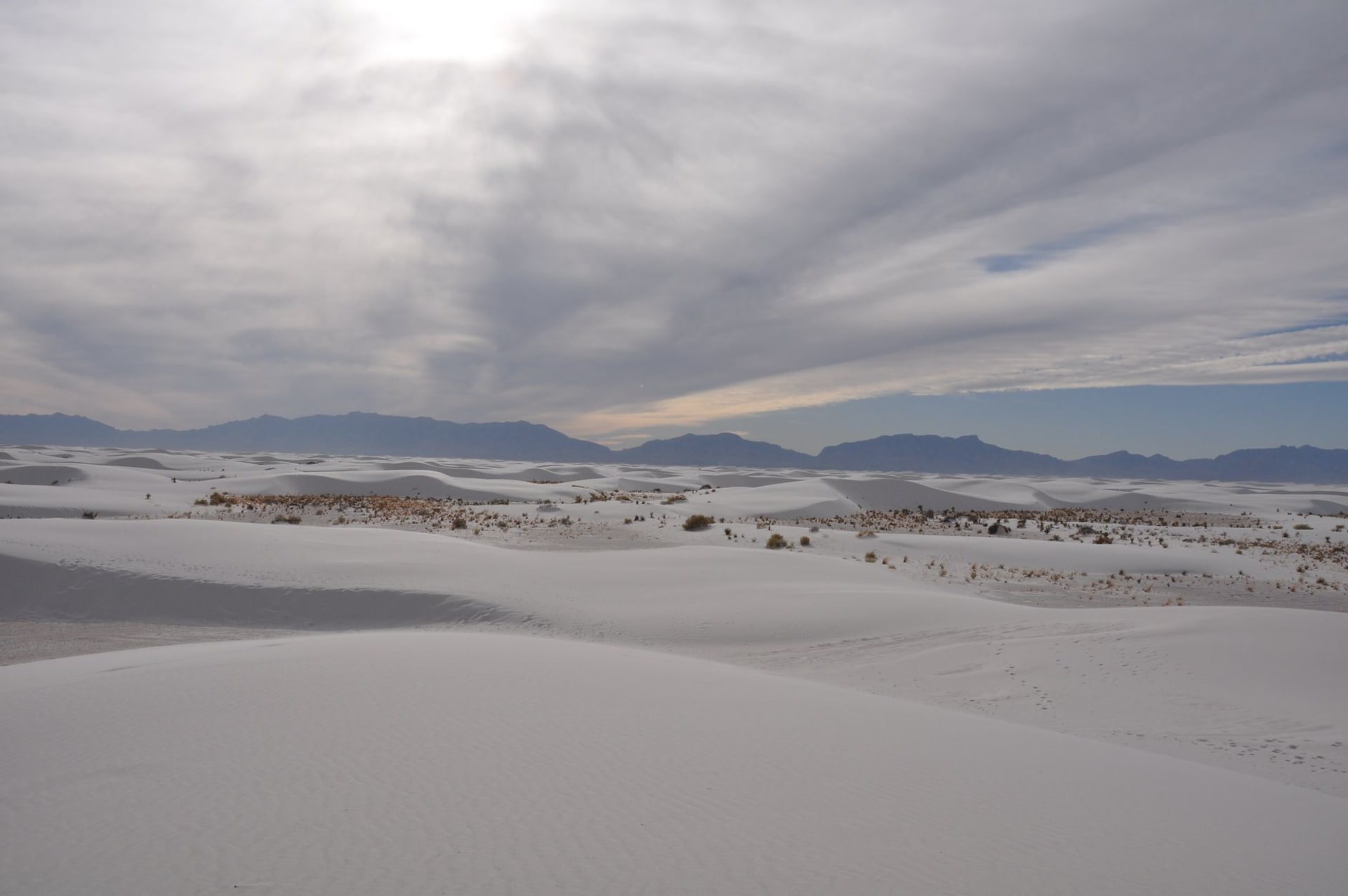 Vast white gypsum dunes at White Sands National Park glowing soft pink at sunset with a pale blue sky