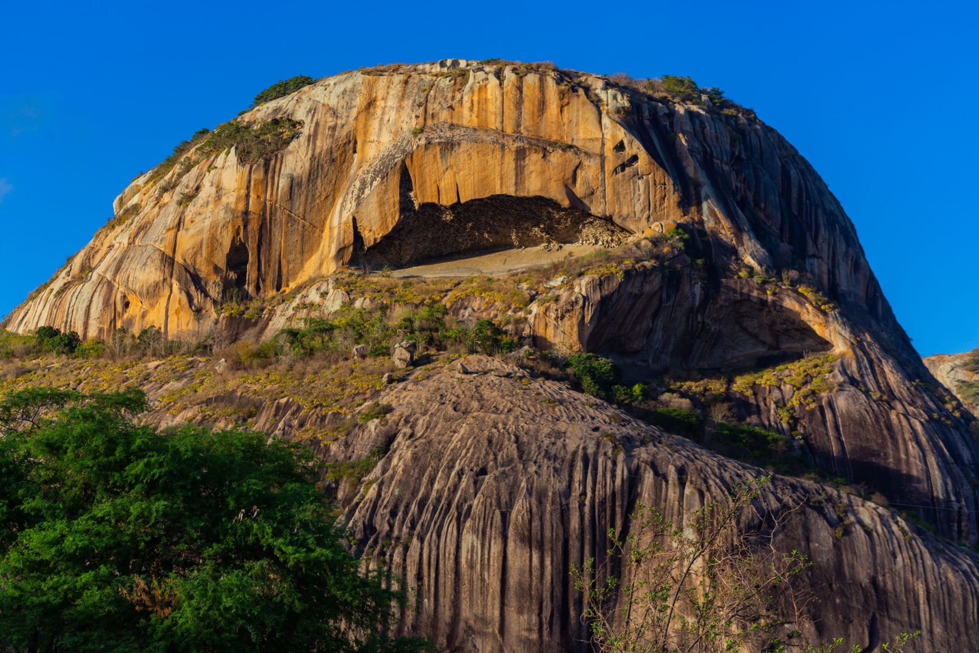 The Black Rocks of Pungo Andongo rising dramatically from the flat savanna, the giant dark granite formations silhouetted against a wide African sky
