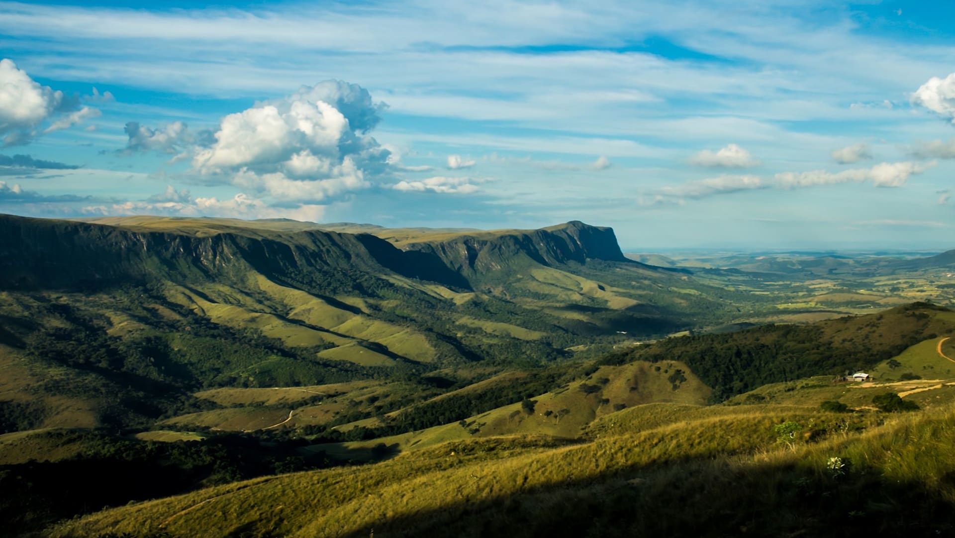 The Serra da Leba mountain pass seen from above, the hairpin switchbacks cutting down the escarpment through green vegetation into the pale coastal haze far below