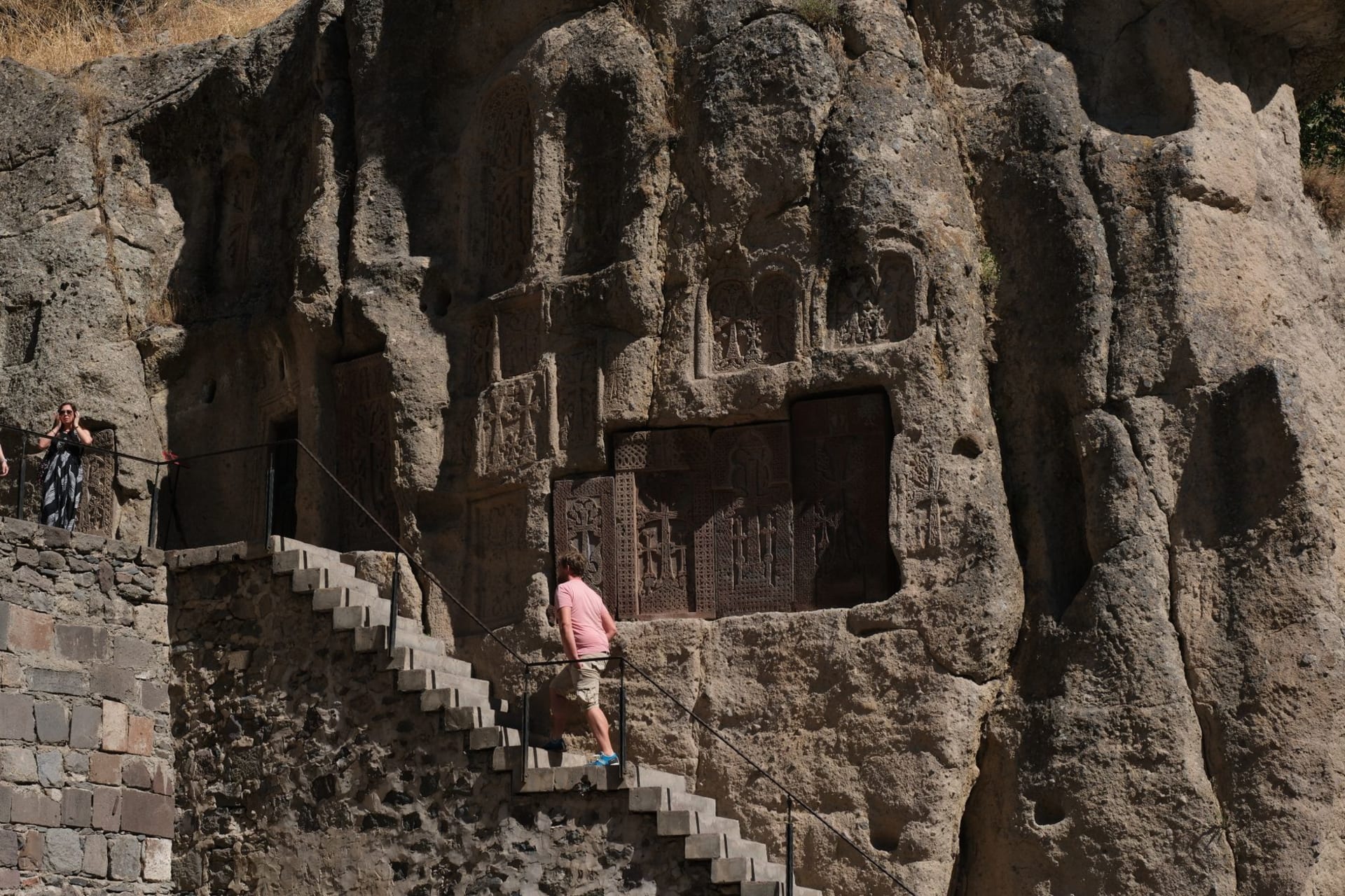 Visitors exploring the ancient rock-hewn carvings at Geghard Monastery Armenia