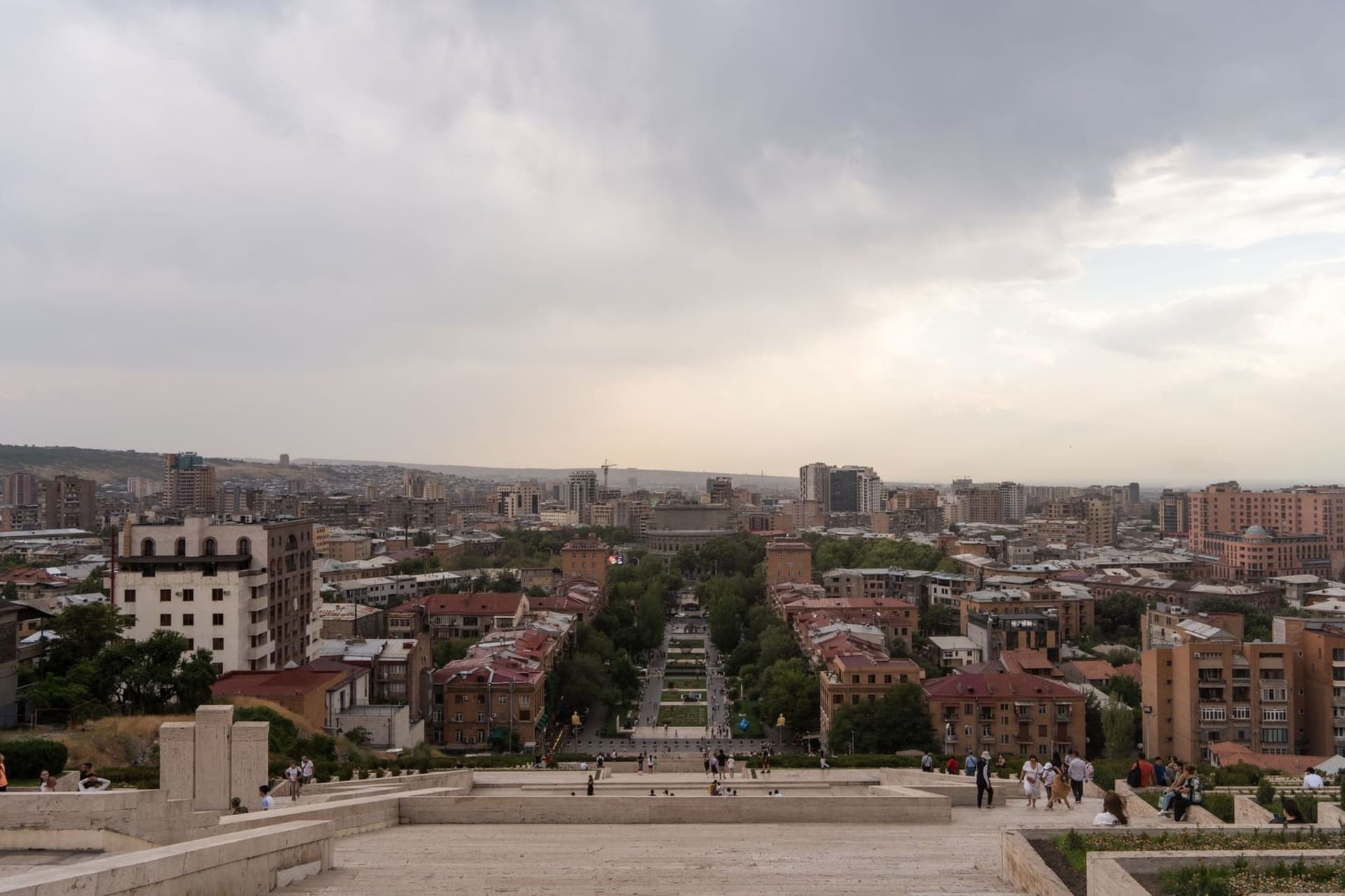 The terracotta-pink facades of Republic Square bathed in late afternoon light, with the distant snow-capped silhouette of Mount Ararat rising above the Yerevan skyline.