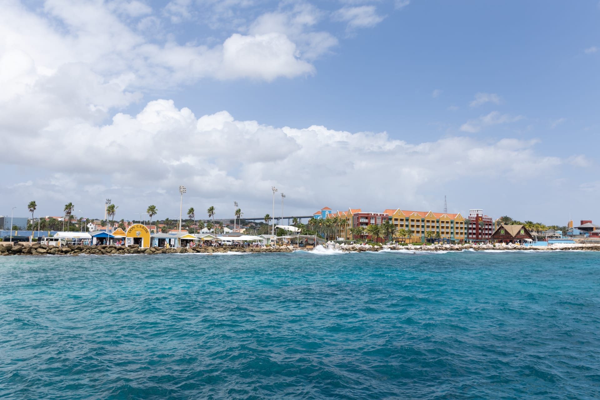 Colorful Dutch colonial buildings in pastel yellow and orange lining an Oranjestad street with bougainvillea spilling from upper floors