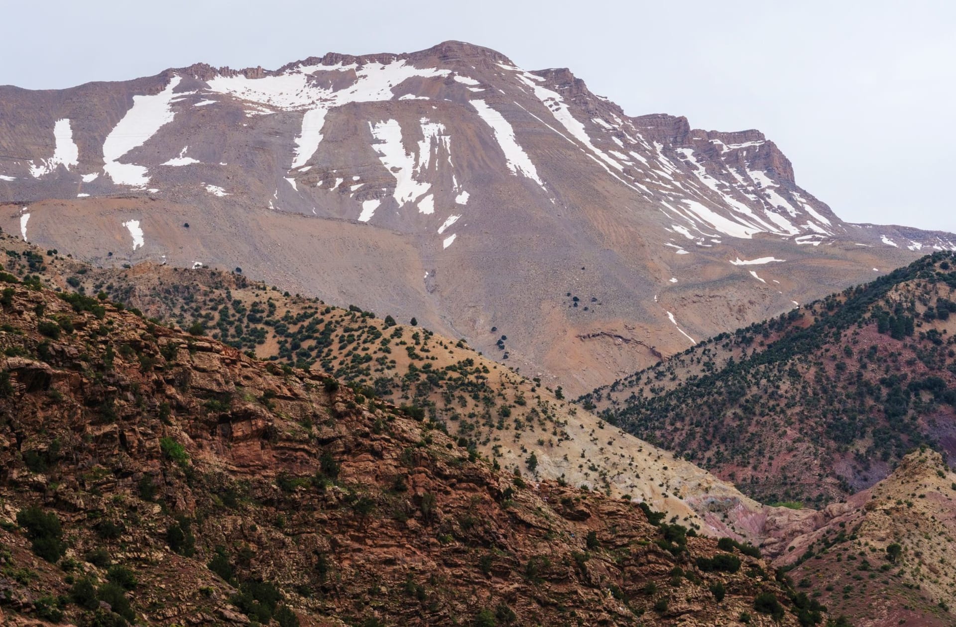 Tizi n'Test mountain pass road winding along a vertiginous ridge with the Souss Valley visible far below in golden afternoon light
