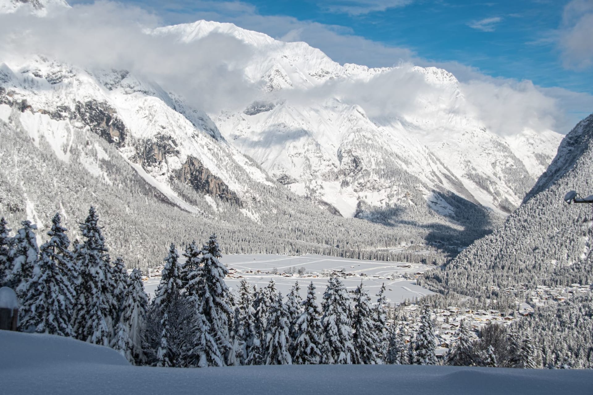 The upper Ötztal valley in late September with copper-colored larch forests on the lower slopes and grey limestone peaks above, a small farm visible in the foreground meadow
