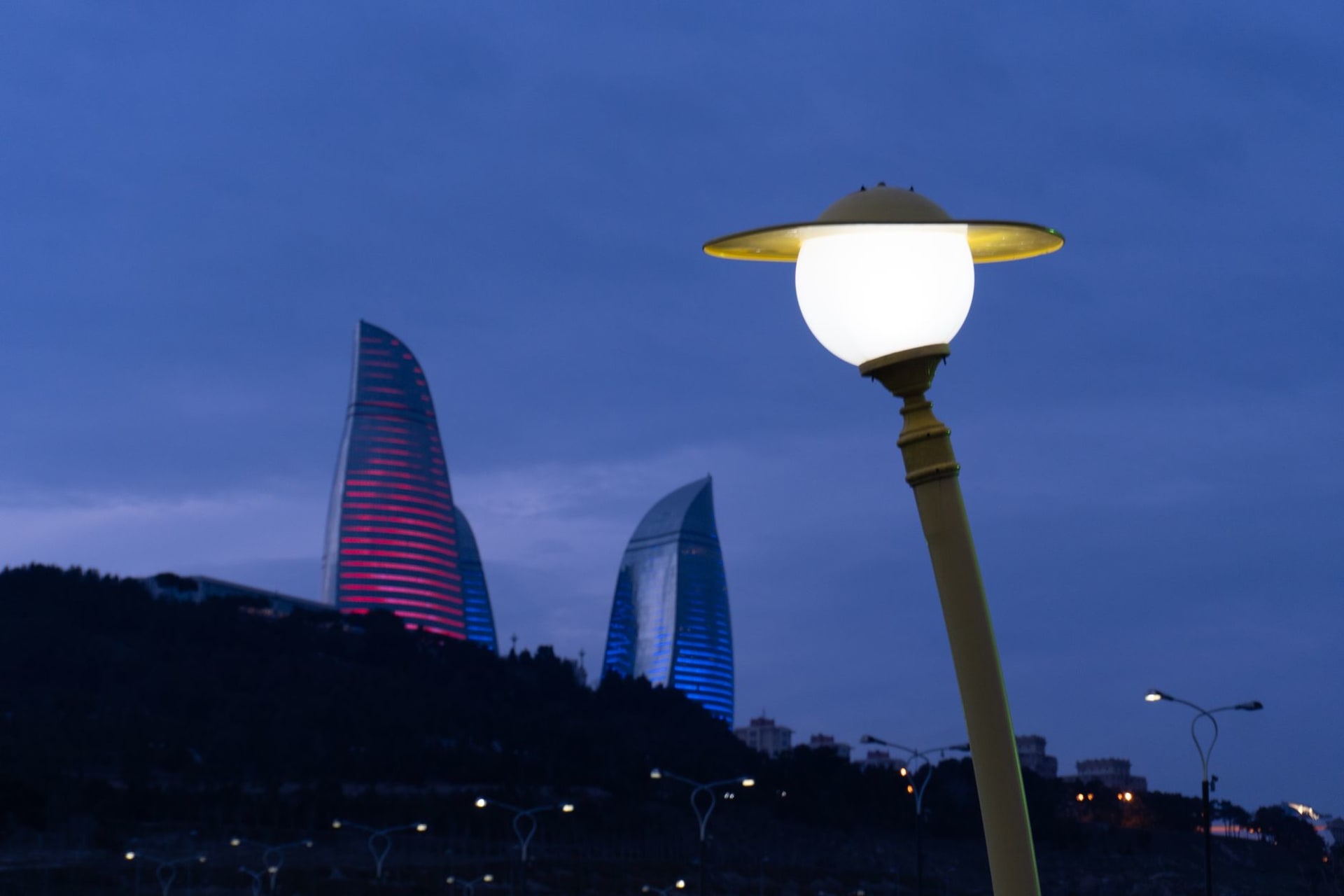 A long line of orange flames rising directly from the base of a dark, bare hillside at dusk on the Absheron peninsula near Baku, Azerbaijan.