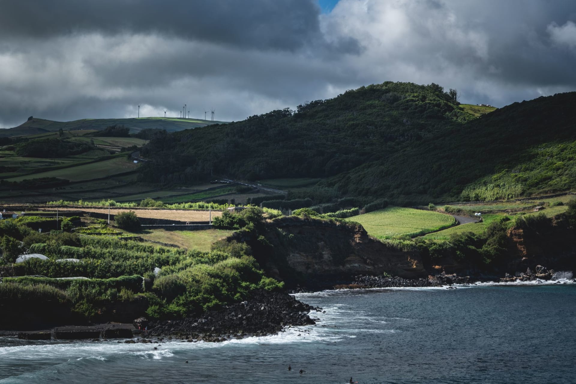 Dramatic waterfall cascading from green clifftops directly into a turquoise Atlantic cove on Flores Island, Azores