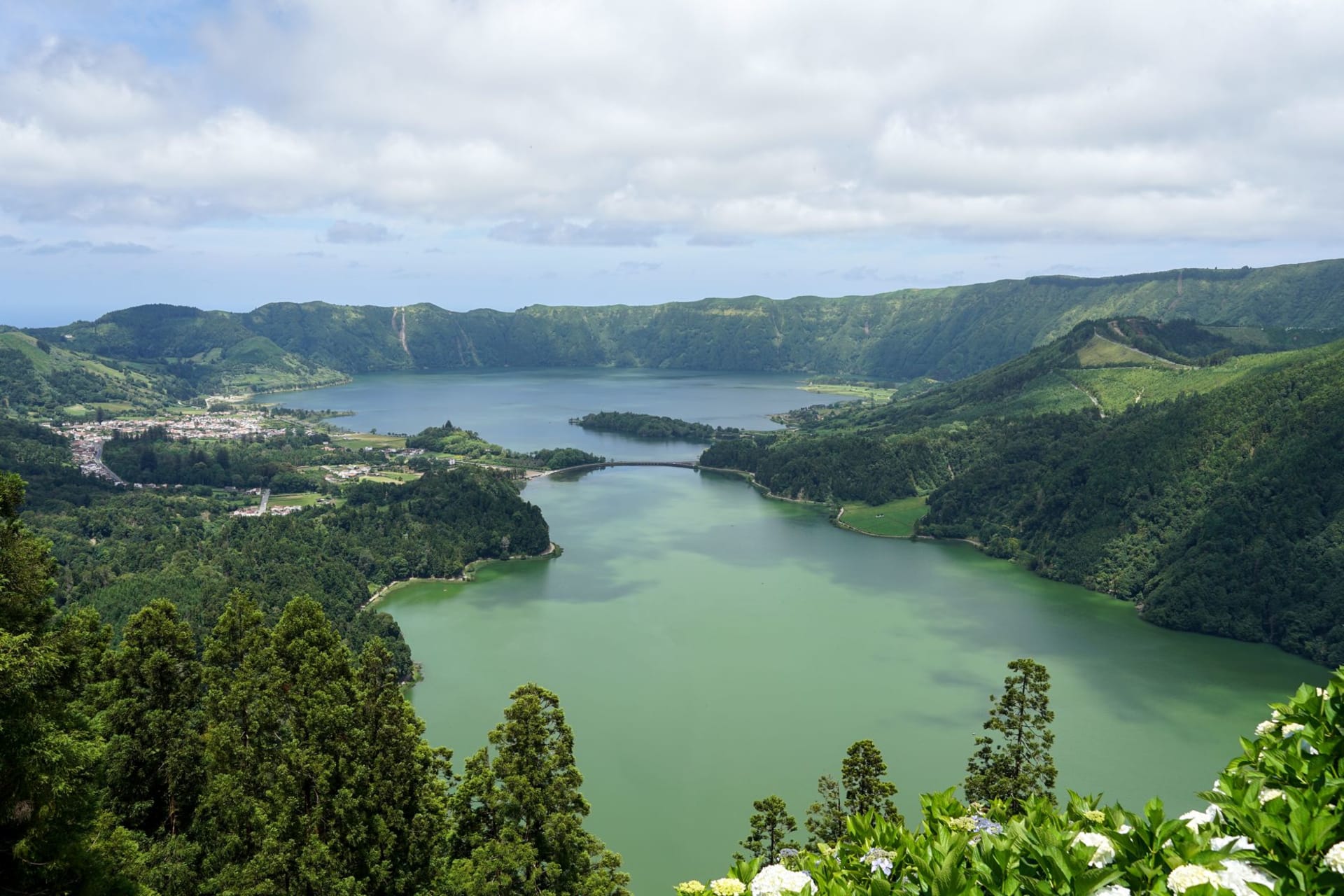 Aerial view of Sete Cidades twin crater lakes surrounded by dense green forest and rolling mist, São Miguel island