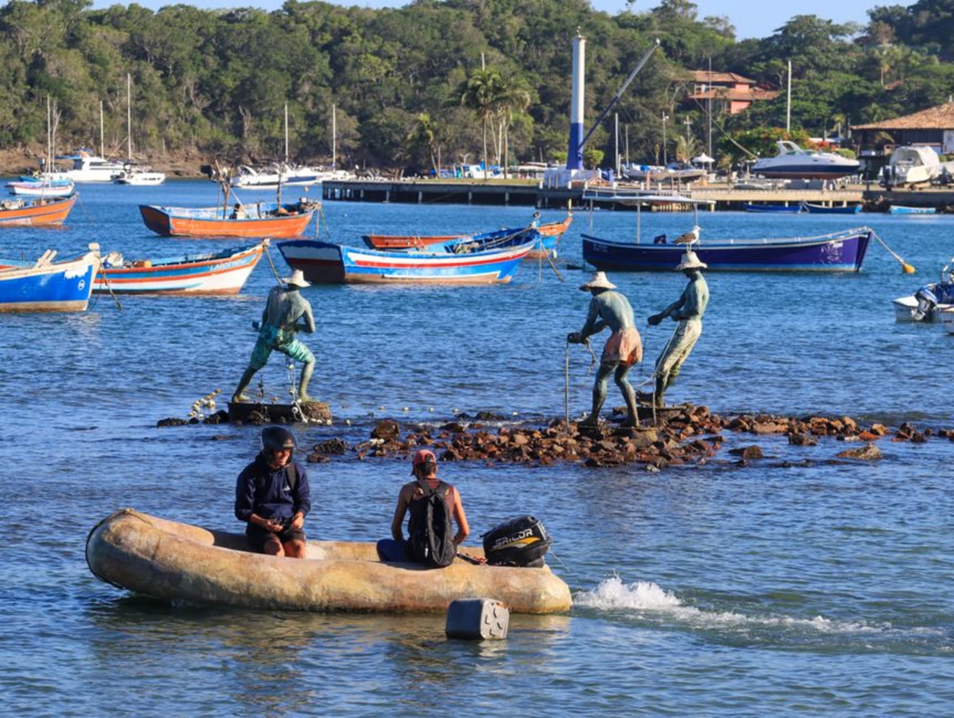 Wooden fishing boats moored along the shore of Ilha de Itaparica with Salvador visible across the bay