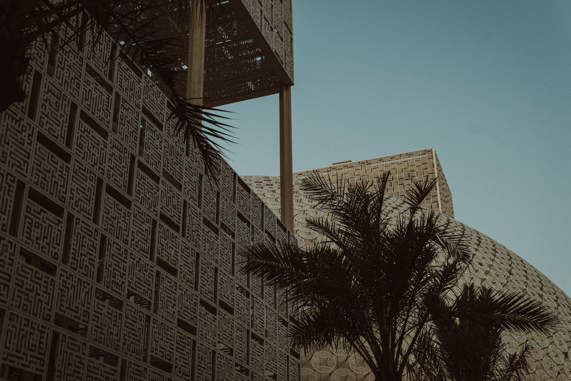 Palm-shaded courtyard of the Jasra Handicraft House, a weaver at a wooden loom in warm morning light